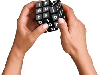 Hands holding a black and white letter and number puzzle cube against a black background